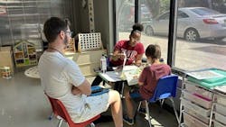 Two Acclaim Autism specialists work with a child. Two Acclaim Autism specialists work with a child.