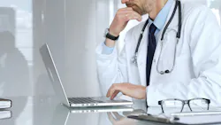 A doctor working on a laptop in a medical office focusing on patient data and healthcare documentation.